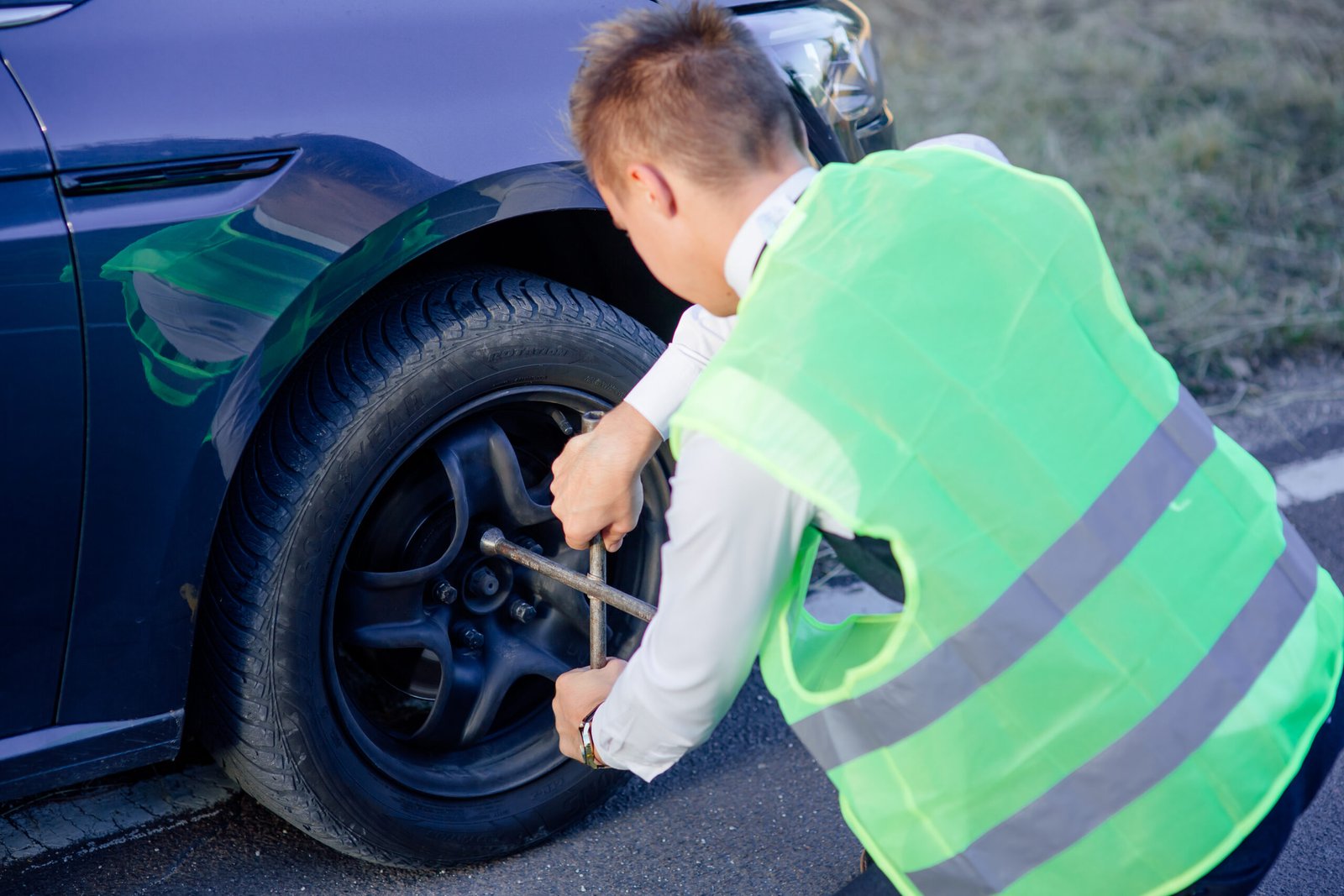 Man changing wheel on the car at the side of the road. Transportation, traveling concept.  unscrews the wheel nuts with a wrench